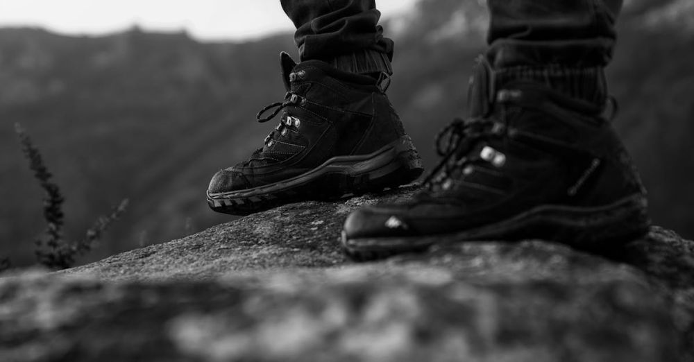 Hiking Boots - Close-up of hiking boots standing on a rock, showcasing outdoor adventure style in monochrome.