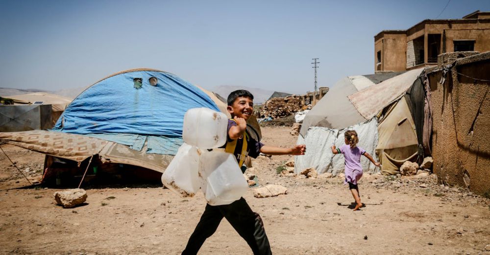 Water Jugs - Children in Idlib refugee camp carrying water jugs, smiling and walking.