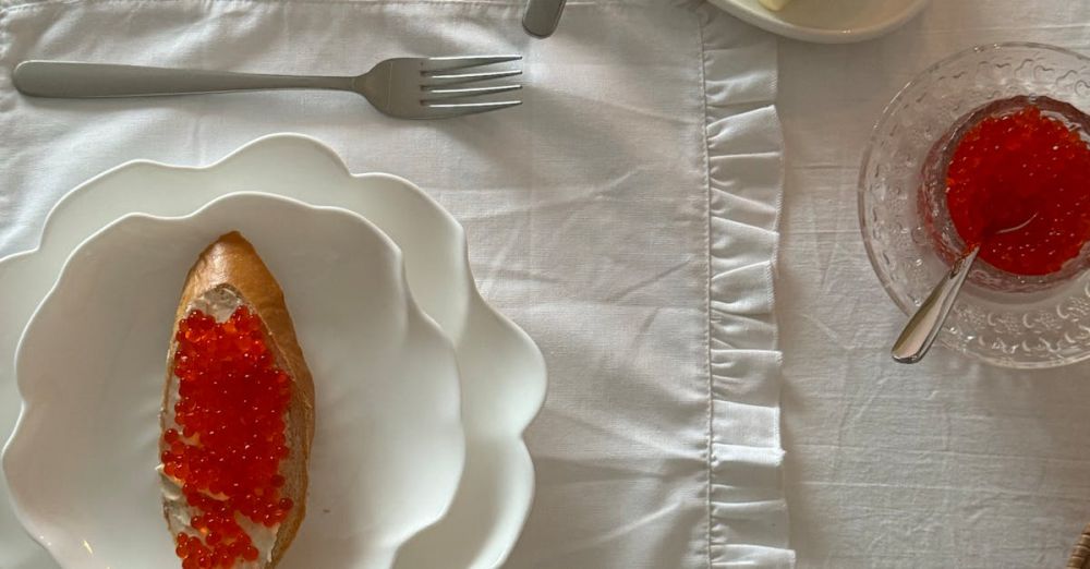 Dish Sets - Stylish table setting with bread and red caviar, butter, and crystal glass in daylight.