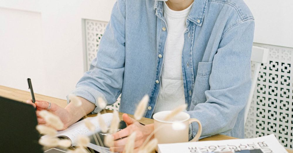 Face Masks - A woman in a face mask uses her laptop in a cozy home office setting.