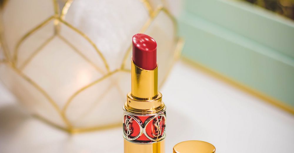 Lip Balms - Luxurious red lipstick in gold tube on a reflective makeup table, epitomizing elegance and beauty.