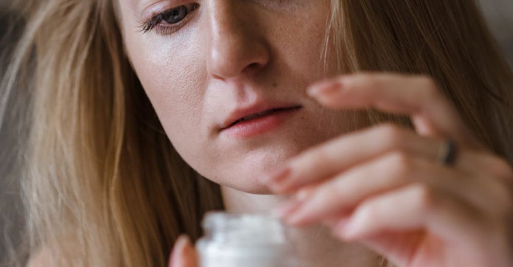 Hair Masks - A young woman applying moisturizing cream indoors, focusing on her skincare routine.