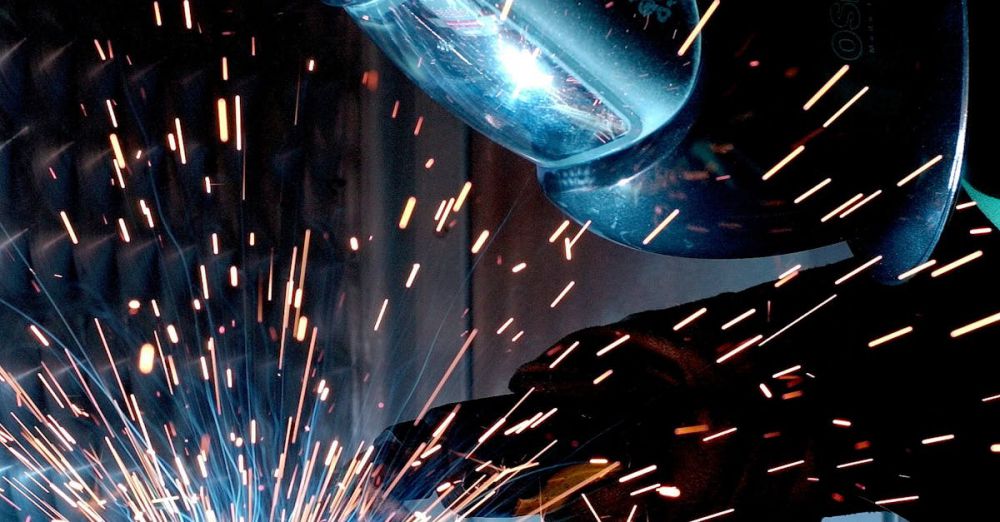 Heat Protectants - A focused welder works with metal in an industrial setting, creating vibrant sparks.