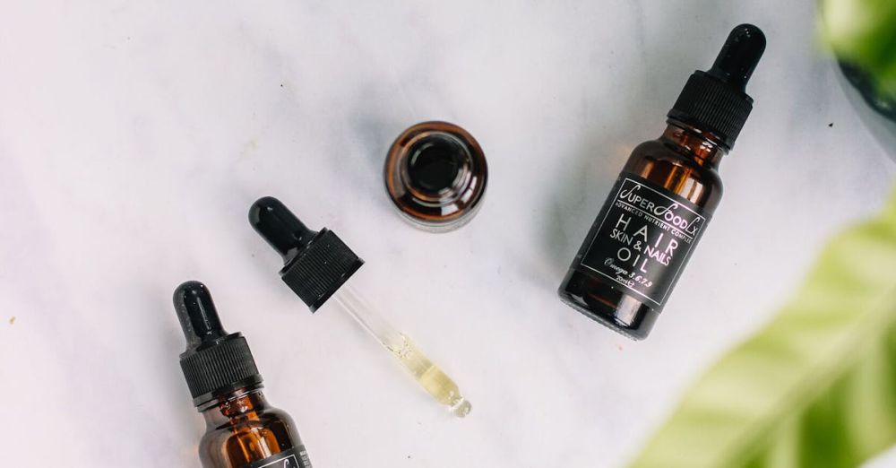 Hair Oils - Flat lay of organic hair oil bottles with droppers on a marble surface.