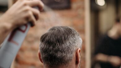 Hairsprays - A professional barber styles a man's hair with hairspray in an urban barbershop.