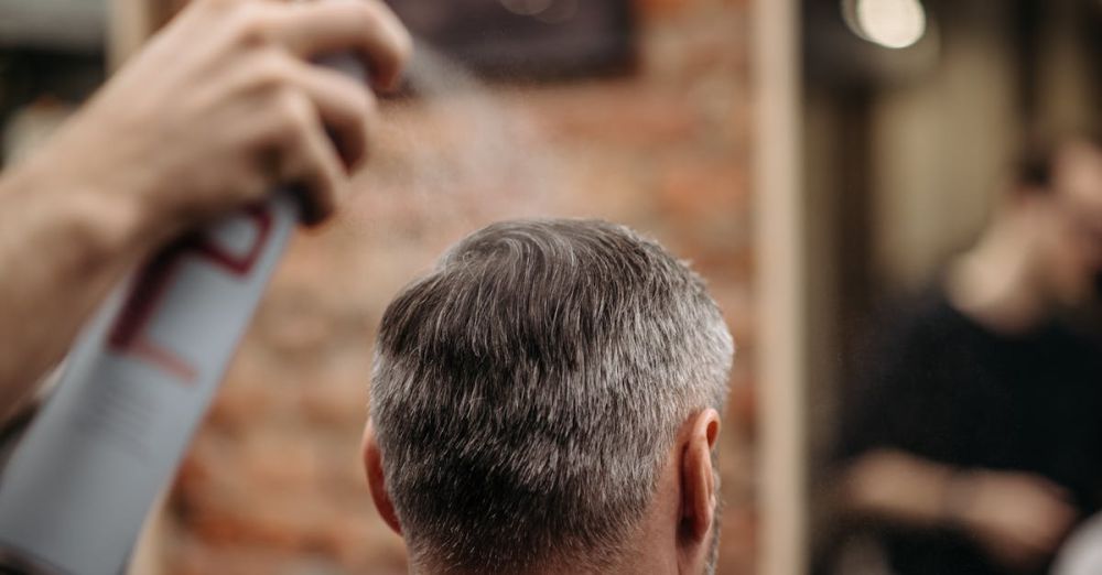 Hairsprays - A professional barber styles a man's hair with hairspray in an urban barbershop.