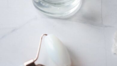 Anti-Dandruff Products - A close-up of skincare products featuring a jade roller and gel in a glass jar, set on marble.