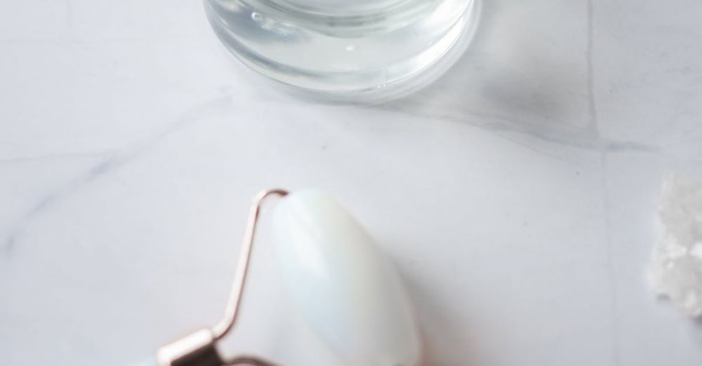 Anti-Dandruff Products - A close-up of skincare products featuring a jade roller and gel in a glass jar, set on marble.