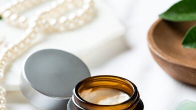 Styling Creams - Elegantly styled under-eye cream jar with pearls and leaves on a white surface.