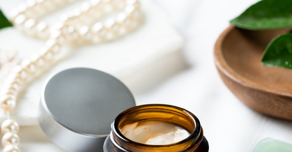 Styling Creams - Elegantly styled under-eye cream jar with pearls and leaves on a white surface.