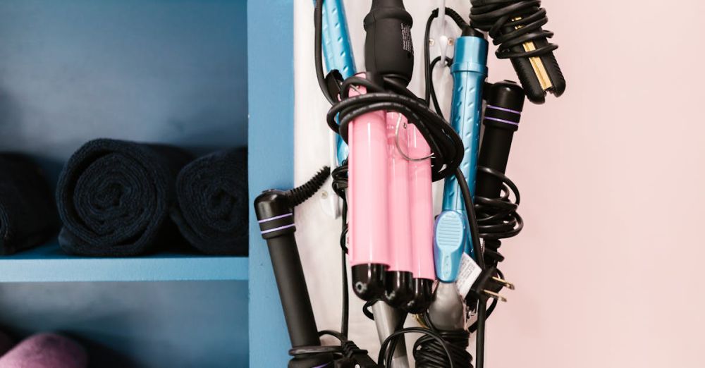 Hairstyling Tools - A vibrant display of curling irons on wall hooks next to neatly stacked salon towels.