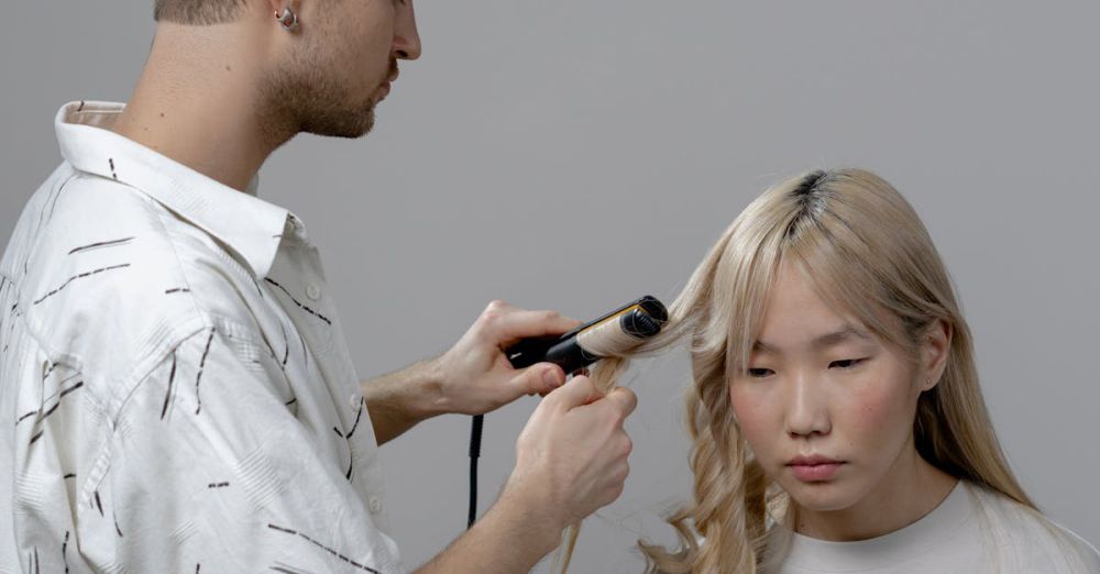 Curling Irons - A hairstylist using a curling iron to style a woman's hair in a salon setting.