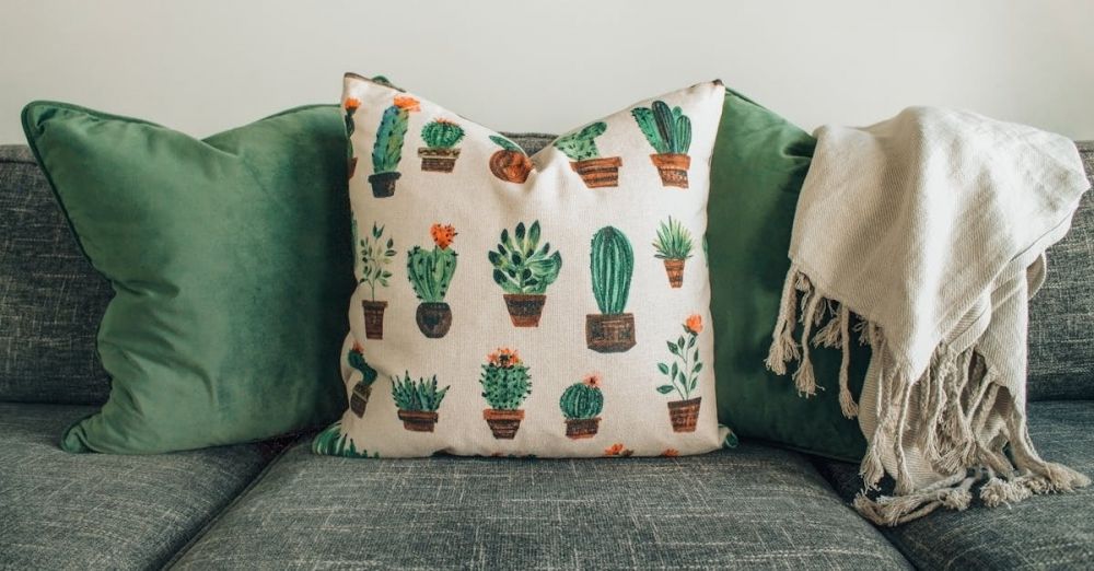 Pillow - A modern living room with green cushions, cactus pillow, and cozy throw blanket on a sofa.