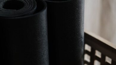 Yoga Mats - Close-up view of black yoga mats rolled and stacked in a wooden basket indoors.