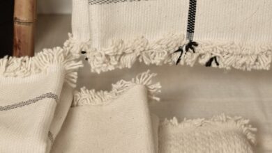 Weighted Blankets - Close-up of neatly stacked neutral cotton and linen textiles, showcasing texture and woven patterns.