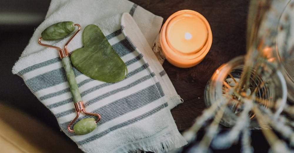 Massage Tools - A serene spa setup featuring a jade roller, gua sha, towel, and candle for ultimate relaxation.