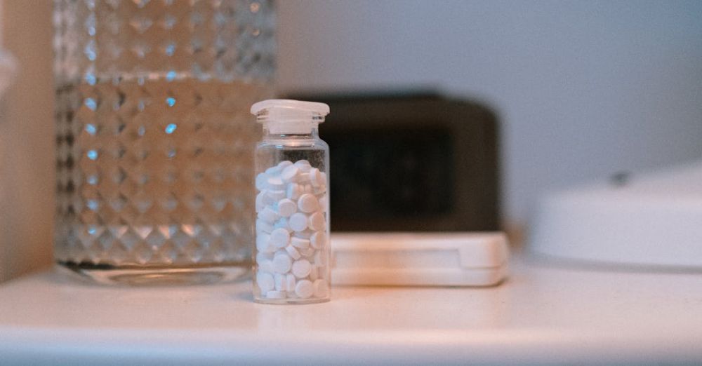 Sleep Supplements - Close-up of a nightstand with a glass of water and a bottle of pills, suggesting evening routine.