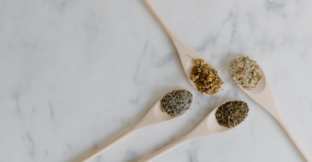 Tea Blends - Top view of wooden spoons with aromatic dried herbs on marble surface.