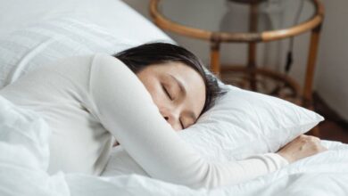 Eye Pillows - A serene scene of a woman sleeping peacefully on white bedding in a cozy bedroom.