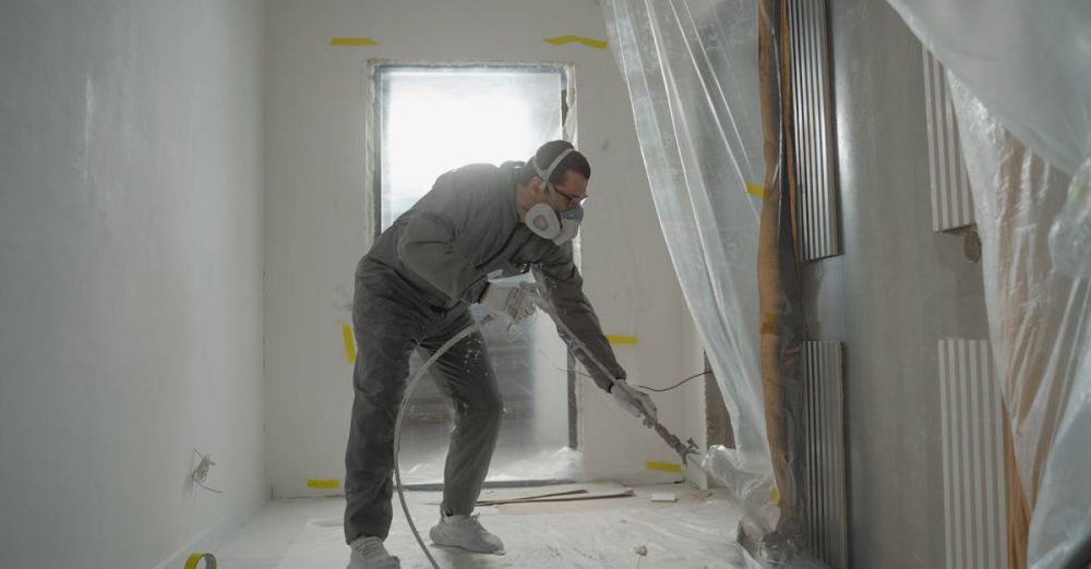 Room Sprays - A worker in protective gear painting walls during an indoor renovation project.