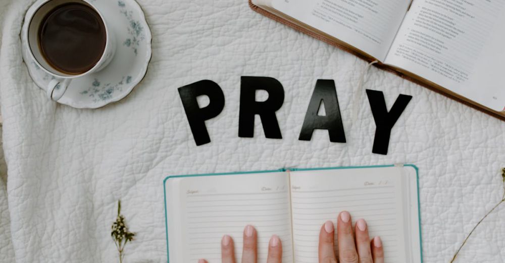 Wellness Journals - A serene flat lay featuring an open Bible, a journal, and a cup of coffee with the word 'PRAY'.