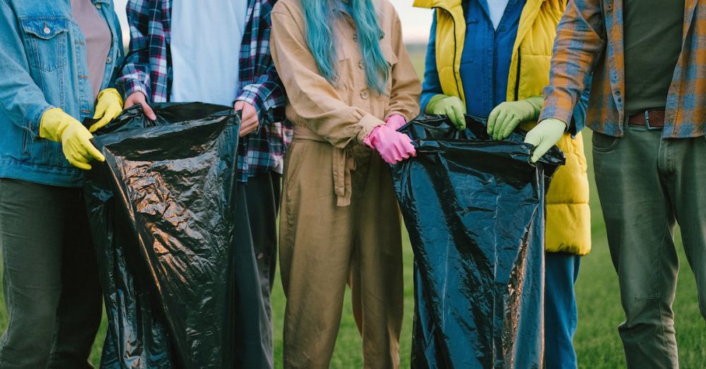 Trash Bags - Diverse volunteers cleaning up a field, holding large trash bags and wearing gloves.