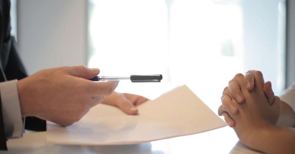 Insurance - Close-up of a contract signing with hands over documents. Professional business interaction.