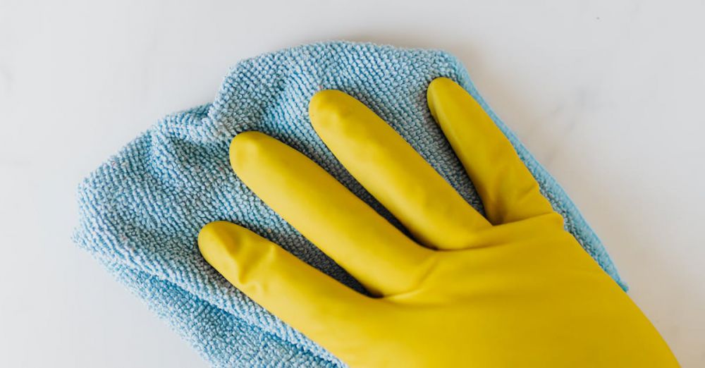 Cleaning Tools - Yellow gloved hand wiping surface with blue cloth, concept of cleaning and hygiene.