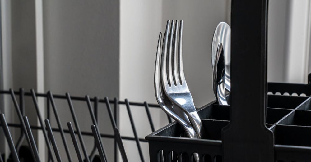 Cleaning Gadgets - Close-up of stainless steel forks in a dishwasher rack, reflecting light and showcasing modern kitchenware.