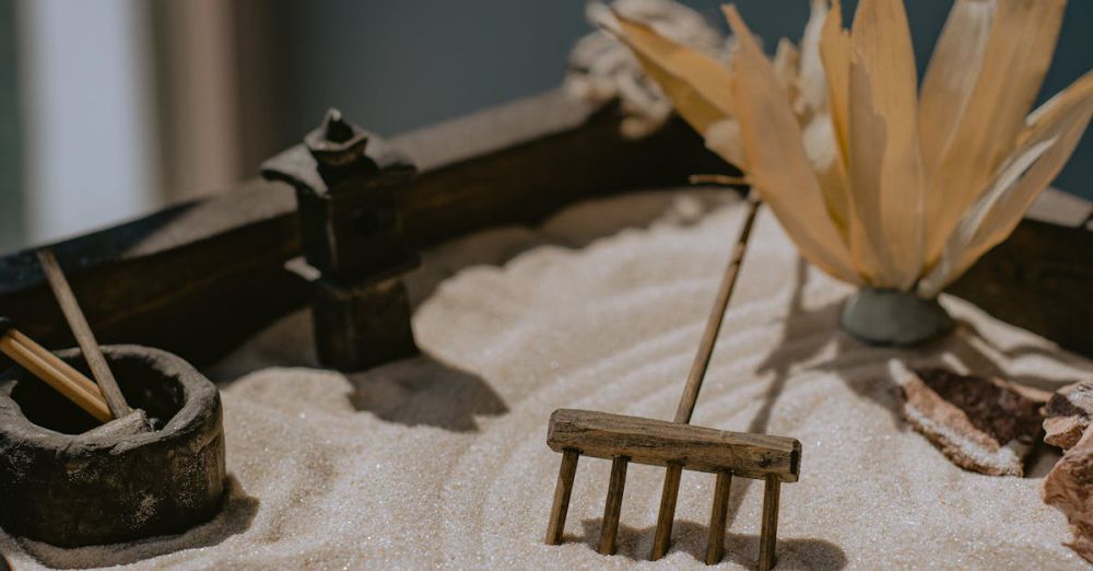 Rakes - Tranquil miniature Zen garden with a sand rake, rocks, and dried plant decoration.