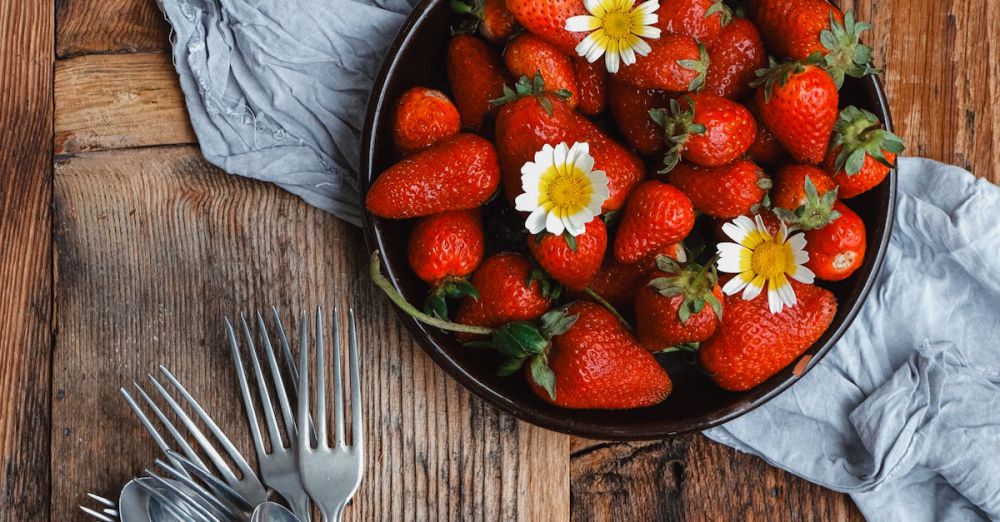 Garden Forks - Bowl of strawberries on wooden table with vintage cutlery and cloth in rustic setting.