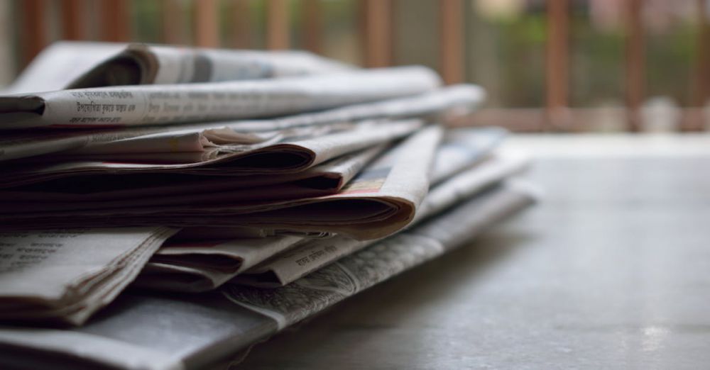 Journals - A close-up of a stack of newspapers resting on a desk, symbolizing information and media.