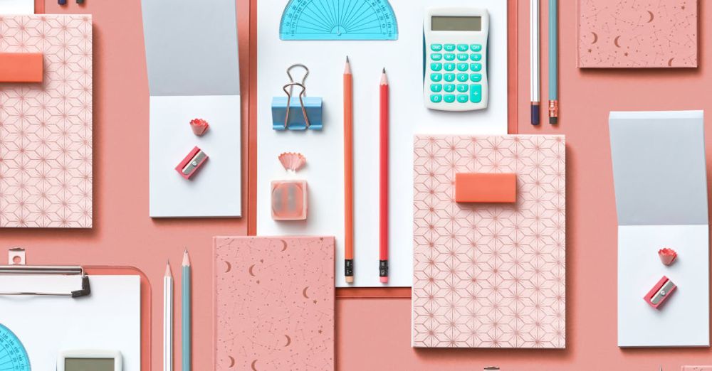 Stationery Sets - Colorful assortment of stationery items arranged on a pink background in a flat lay style.