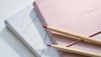 Journal - Close-up of a pink journal with pencils on a marble top. Perfect for note-taking or planning.