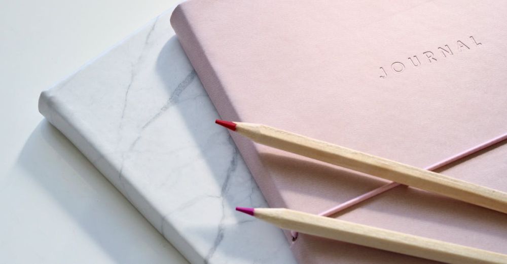 Journal - Close-up of a pink journal with pencils on a marble top. Perfect for note-taking or planning.