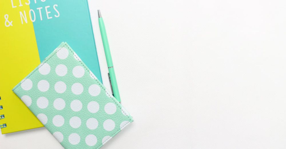 Diaries - Flatlay of a polka dot wallet, pen, and notebook with copyspace on a white background.