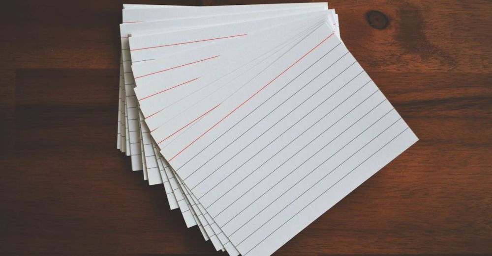 Index Cards - High-angle view of blank index cards arranged neatly on a wooden desk, ideal for education and organization concepts.