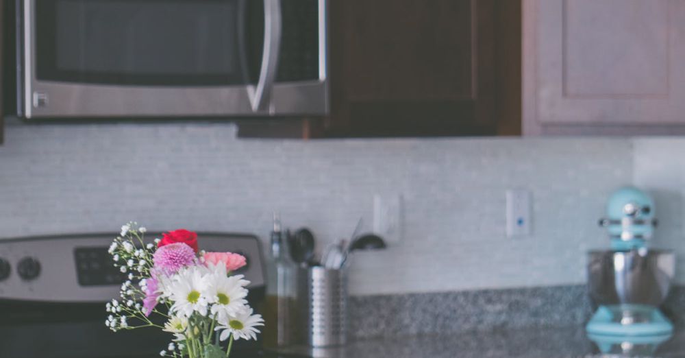 Cookware Sets - Stylish kitchen interior featuring granite countertops, dark wood cabinets, and a floral vase centerpiece.