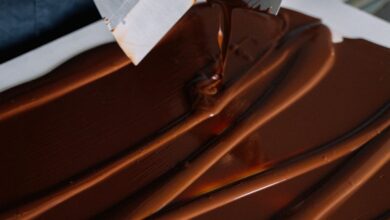 Spatulas - Hand spreading chocolate smoothly with spatulas on a flat surface for dessert preparation.