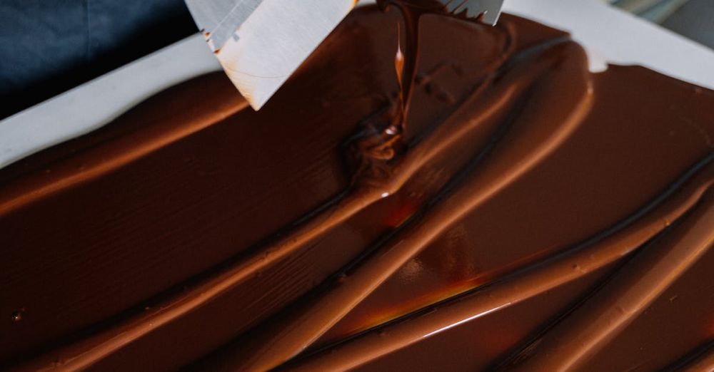 Spatulas - Hand spreading chocolate smoothly with spatulas on a flat surface for dessert preparation.