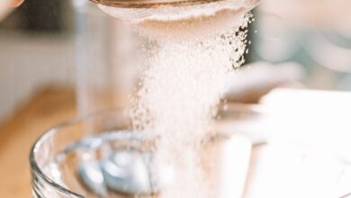 Flour Sifters - Flour being sifted into a clear glass bowl, showcasing baking preparation.