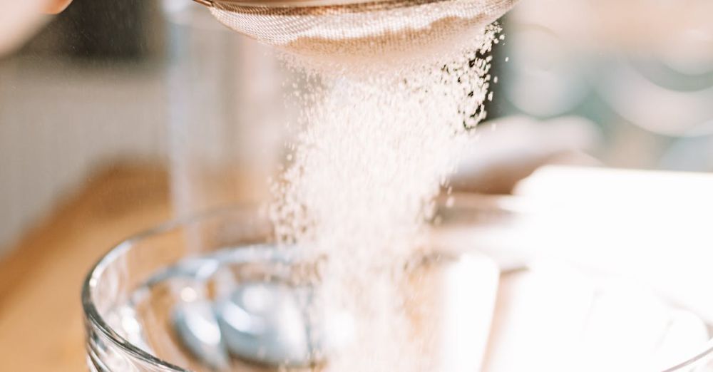 Flour Sifters - Flour being sifted into a clear glass bowl, showcasing baking preparation.