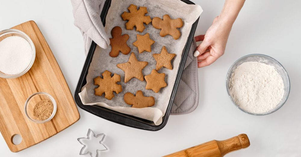 Cookie Cutters - Overhead view of gingerbread cookies on a baking tray with ingredients and cookie cutters.