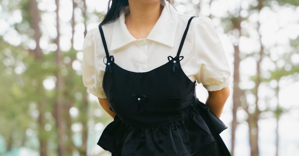 Hooks - Young woman in black dress poses in a serene forest, showcasing a modern fashion style.