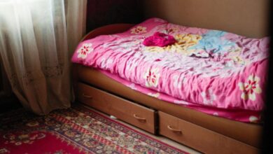 Under-Bed Storage - A warm and inviting bedroom scene featuring a floral pink bedspread, under-bed drawers, and a patterned rug.