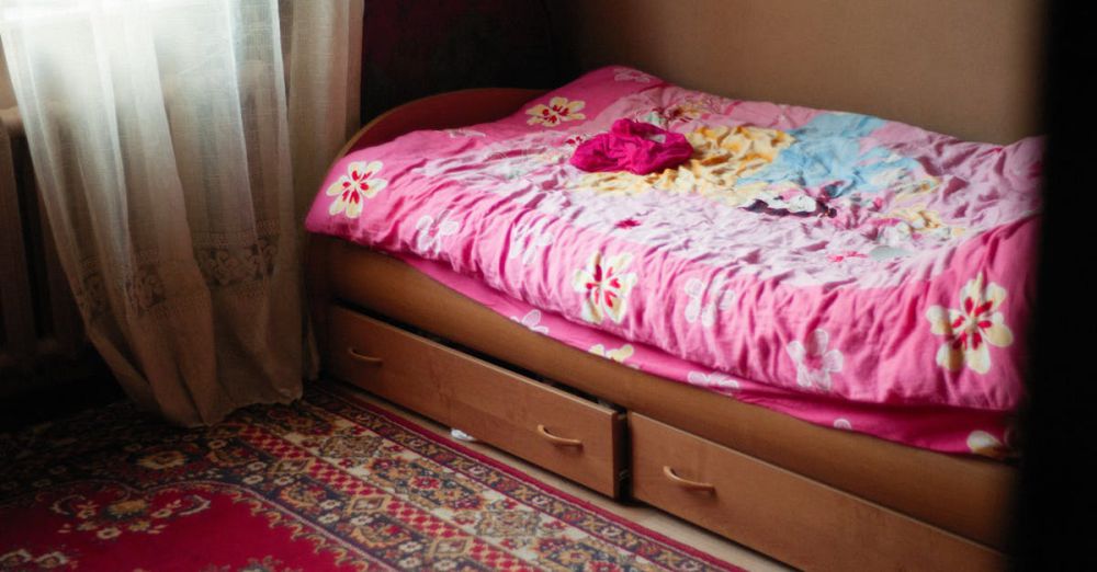 Under-Bed Storage - A warm and inviting bedroom scene featuring a floral pink bedspread, under-bed drawers, and a patterned rug.