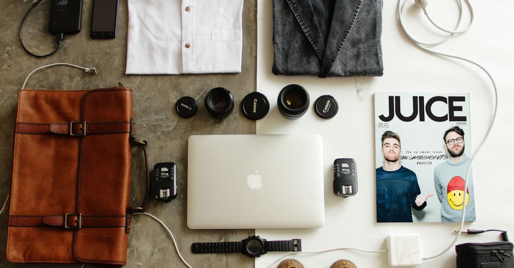 Packing - Neatly arranged travel essentials for men including clothing, tech gear, and a magazine.