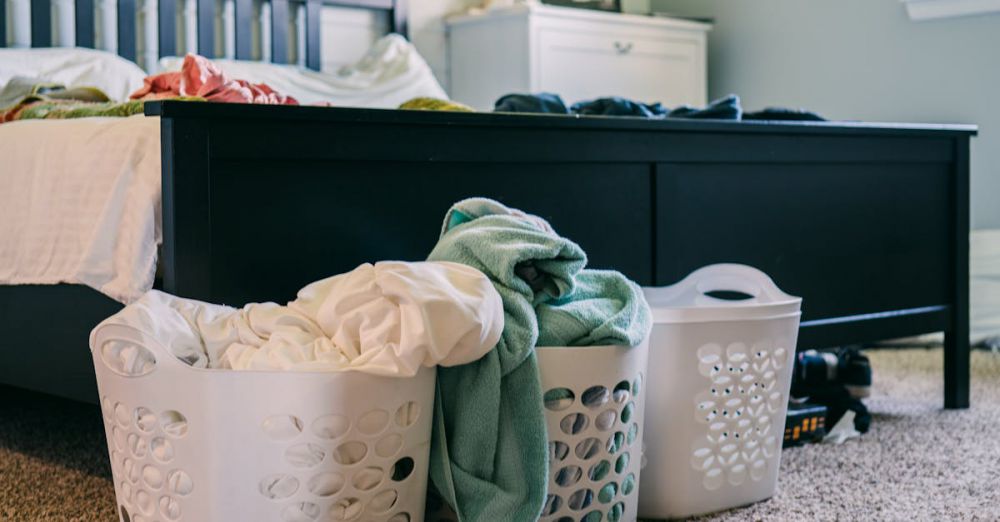 Hampers - A cozy bedroom scene featuring laundry baskets filled with clothing, placed on a carpeted floor.