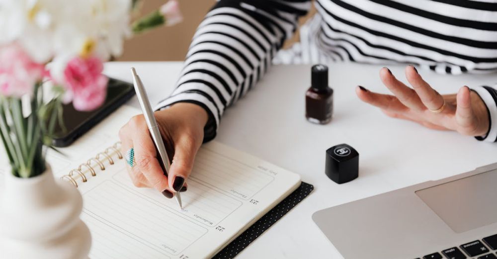 Jewelry Organizers - Unrecognizable female using pen and writing notes in notepad while sitting at table and waiting when polish nail getting dry