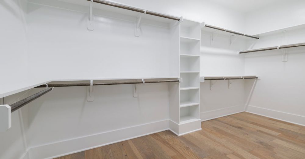 Closet Rods - Modern empty walk-in closet with wooden flooring and white shelving.